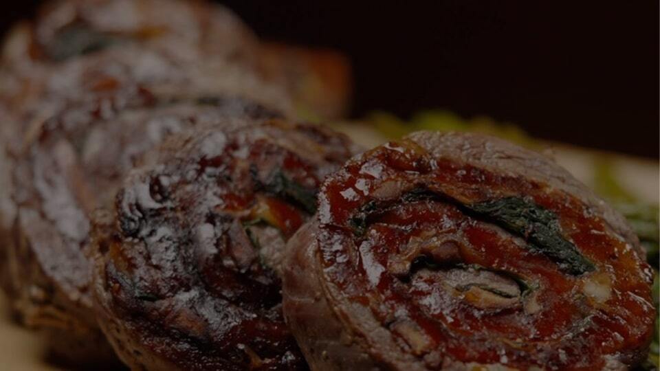 Close-up of a stuffed meat roll with spinach and peppers, sliced into rounds